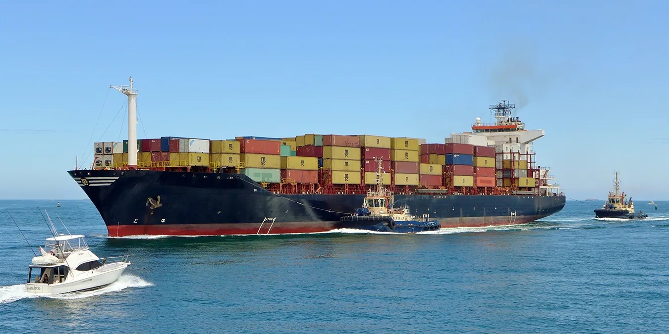 Cargo ship escorted by tug boats